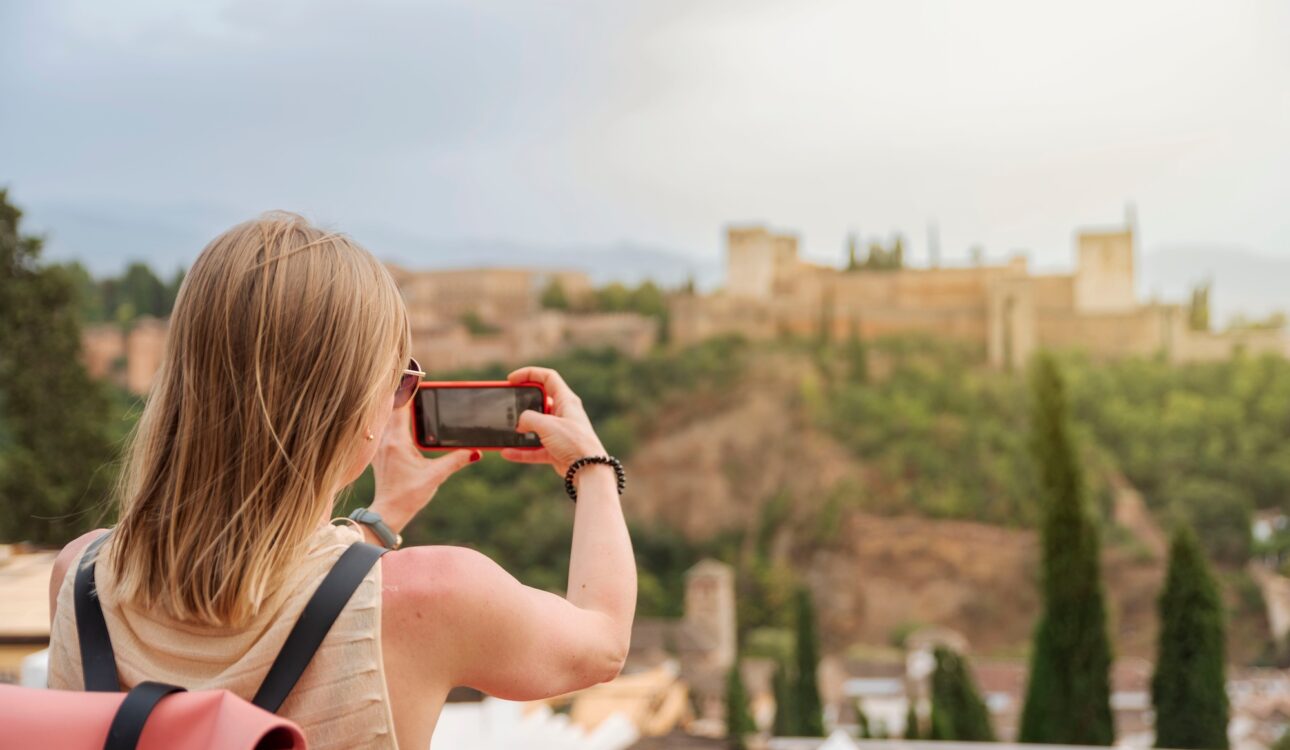 Young blonde female tourist taking the picture of Alhambra in Granada, Spain