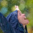 Cropped shot of a young woman standing happily in the rain in her raincoat