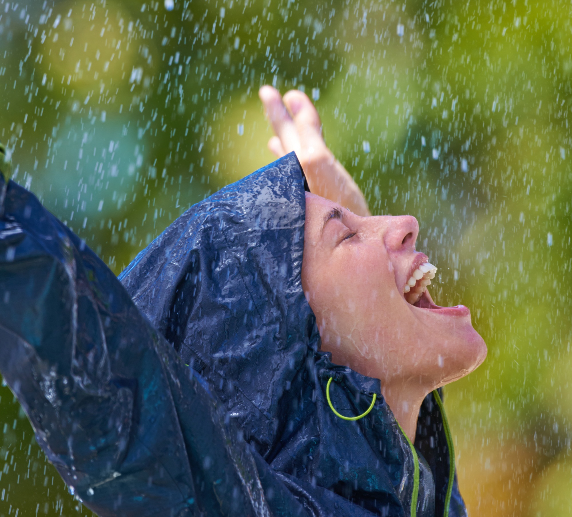 Cropped shot of a young woman standing happily in the rain in her raincoat