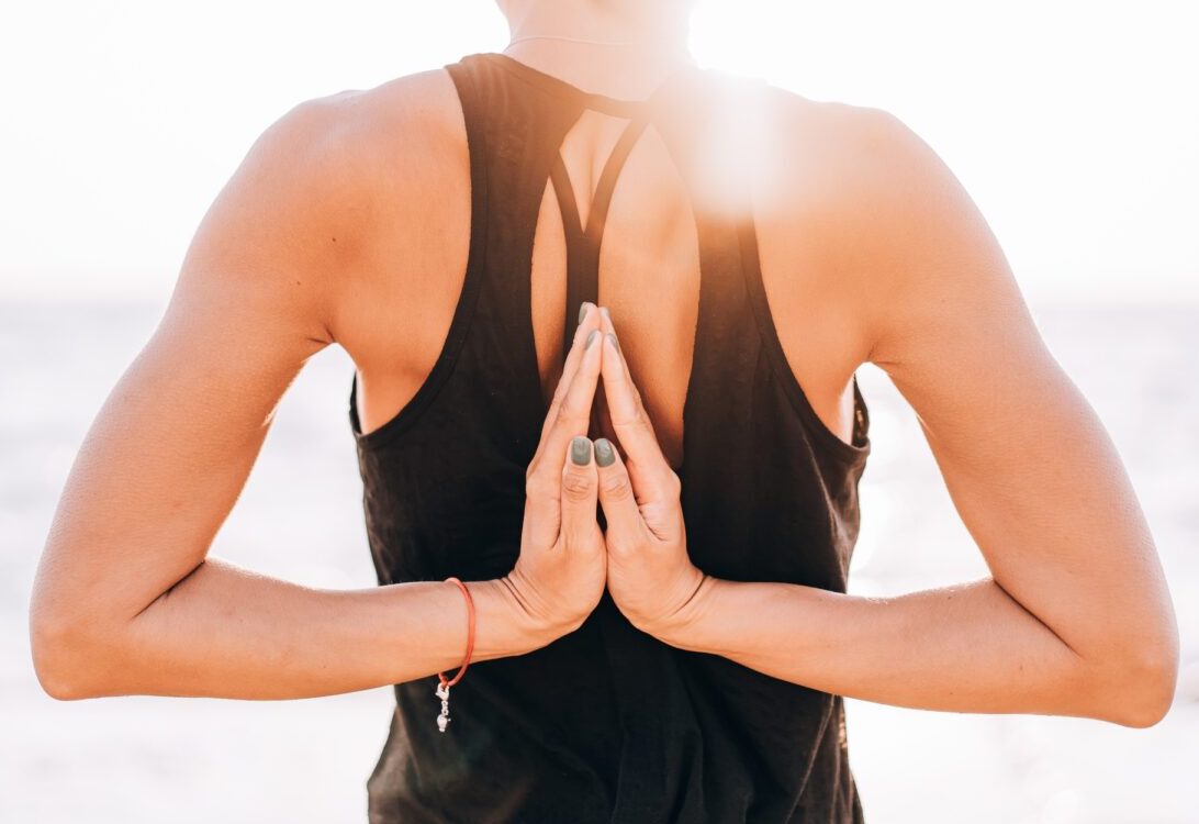 woman makes greeting to the sun at sunrise. Hands in back namaste. Yoga, meditation,