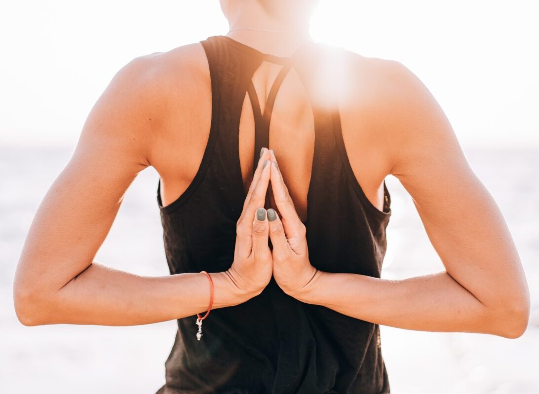 woman makes greeting to the sun at sunrise. Hands in back namaste. Yoga, meditation,