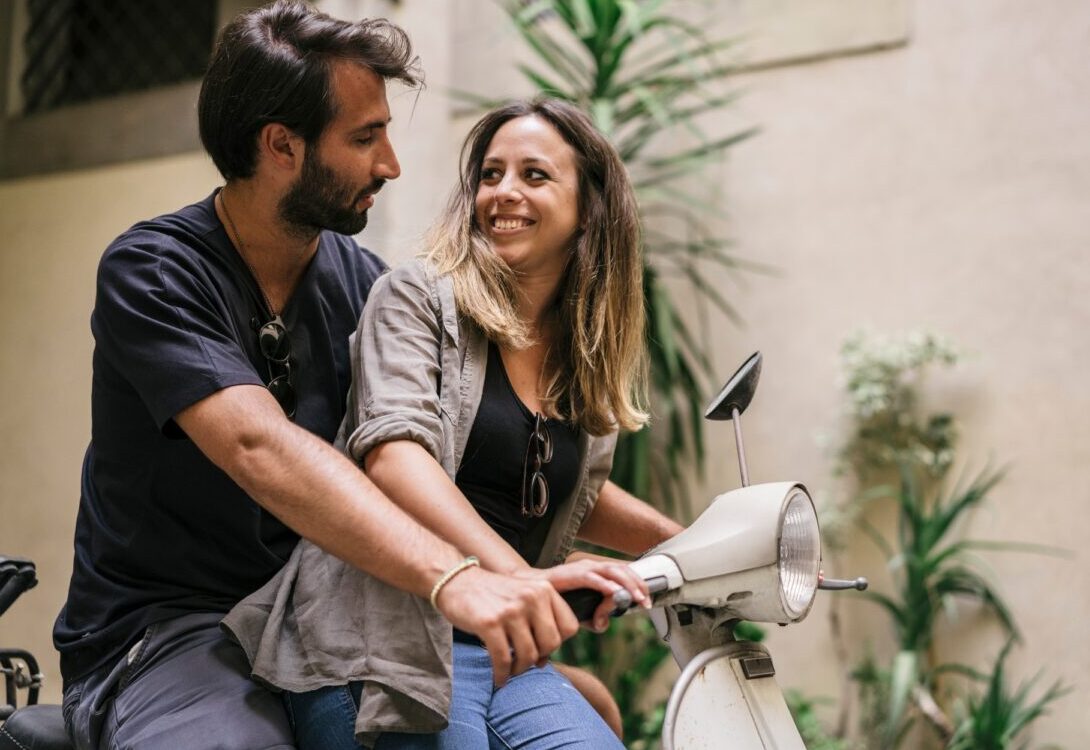 Young caucasian couple riding a vintage vespa in Granada
